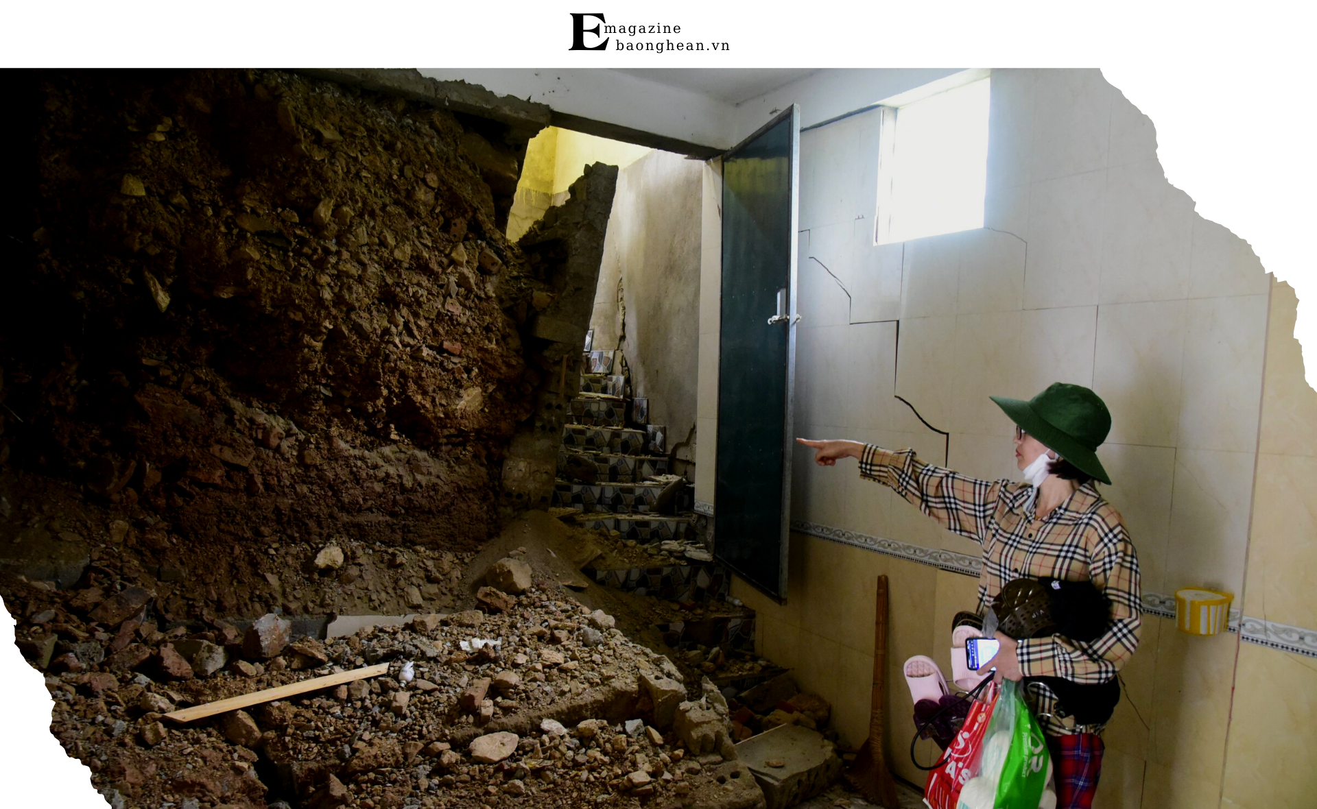 Cô Nguyễn Thị Hoài trong căn nhà mới hoàn thành chưa đầy 1 năm, bên mảng tường đổ sập do vết nứt trên núi sau lũ. Ảnh: Minh Quân. 