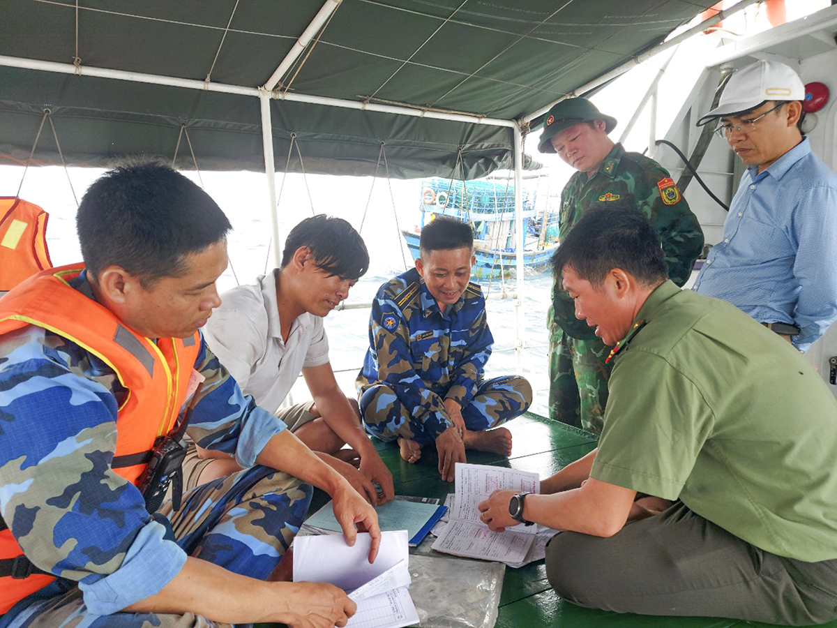 Các thành viên Đoàn công tác liên ngành làm việc, giải thích các quy định pháp luật với thuyền trưởng tàu cá TH-91674-TS là ông Hoàng Văn Mạnh (áo trắng).